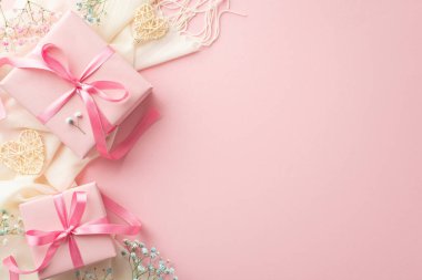 Spring gifts concept. Top view photo of pink present boxes with bows white soft scarf rattan hearts and gypsophila flowers on isolated pastel pink background with empty space