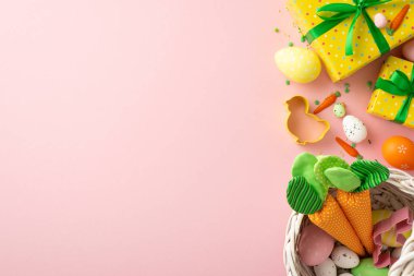 Easter concept. Top view photo of yellow gift boxes with green bows basket with easter eggs carrots chicken shaped baking mold and sprinkles on isolated pastel pink background with empty space