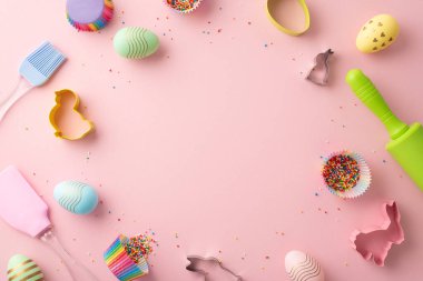 Easter cooking concept. Top view photo of kitchen utensils colorful easter eggs and paper baking molds with sprinkles on isolated pastel pink background with copyspace in the middle