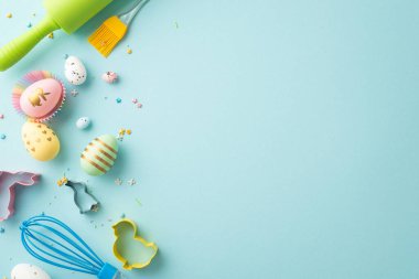 Easter concept. Top view photo of colorful easter eggs in paper baking molds rolling-pin whisk brush and sprinkles on isolated pastel blue background with copyspace