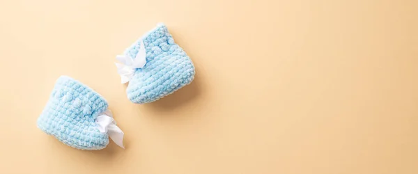 Gender reveal party concept. Top view photo of blue knitted booties on isolated pastel beige background with copyspace