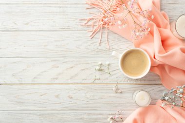 Hello spring concept. Top view photo of cup of fresh coffee candles in glasses gypsophila flowers and pink scarf on grey wooden table background with copyspace