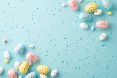 Easter decorations concept. Top view photo of white yellow blue pink easter eggs and sprinkles on isolated pastel blue background with empty space