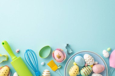 Easter cooking concept. Top view photo of plates with easter eggs kitchen utensils and baking molds on isolated pastel blue background with blank space