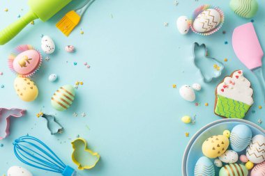 Easter concept. Top view photo of plate with colorful eggs rolling-pin whisk brush silicone spatula baking molds gingerbread and sprinkles on isolated pastel blue background with blank space
