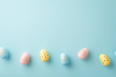 Easter celebration concept. Top view photo of colorful easter eggs in row on isolated pastel blue background with blank space
