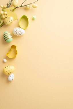 Easter mood concept. Top view vertical photo of colorful easter eggs baking molds and easter plant on isolated pastel beige background with copyspace