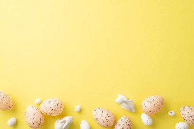 Paskalya dekorasyonu konsepti. Paskalya bıldırcın yumurtalarının ve izole edilmiş sarı arka planda seramik tavşanların fotosu.