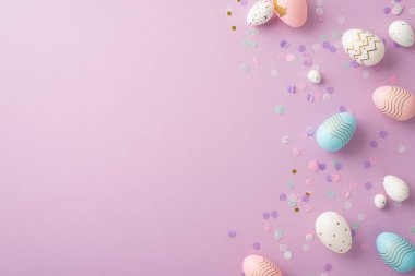 Paskalya kutlaması. Üst görüntüde pembe mavi paskalya yumurtaları ve eflatun arkaplandaki telif boşluğunda konfeti var.