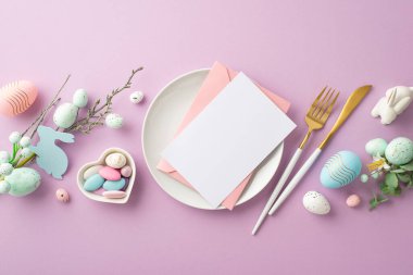 Paskalya konsepti. Pembe zarf ve kağıt kartın plaka çatallı fotoğraf paskalya buketi pembe ve mavi yumurta tabağı içinde tatlılar ve seramik tavşanın izole edilmiş eflatun arkaplanı boş.