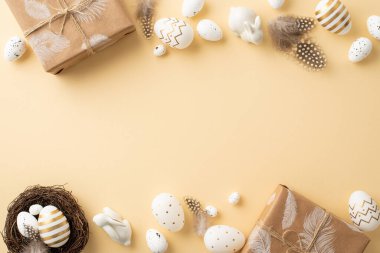 Paskalya konsepti. Beyaz ve altın renkli Paskalya yumurtalarının en iyi fotoğrafı kağıt kutular seramik tavşan bıldırcın yuvası ve kopyalanmış bej arka planda tüyler