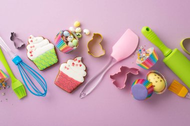 Paskalya yemeği konsepti. Mutfak aletlerinin, fırçaların, merdane fırçalarının, silikon spatula fırçalarının, paskalya yumurtalarının, zencefilli ekmek kağıdının, yalıtılmış leylak arka planda küflerin ve serpintinin en üst görüntüsü.