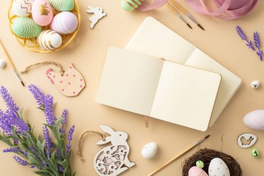 Paskalya konsepti. Çizim bloklarının en üst görüntüsü fırça renkli paskalya yumurtaları kase ahşap tavşanlar tavuk pembe kurdele yuvası ve izole edilmiş bej arka planda bir demet lavanta.