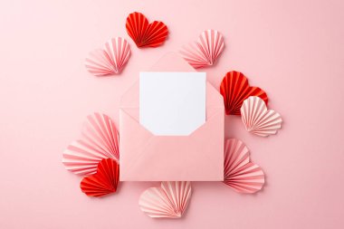 Anneler Günü konsepti. Üst görünüm fotoğraf açık pembe zarf ile mektup ve origami kağıt kalpler izole pastel pembe arka plan ile kopyalanmış