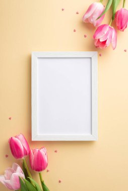 Anneler Günü kutlaması konsepti. Üst görüntü boş fotoğraf çerçevesi buketleri pembe laleler ve izole edilmiş pastel bej arkaplan üzerine kalp şeklinde serpiştirmeler