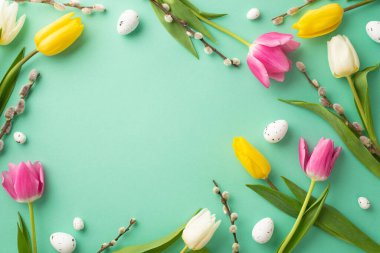 Easter atmosphere concept. Top view photo of quail eggs pussy-willow and colorful tulips on isolated turquoise background with empty space in the middle