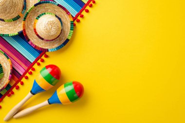 Cinco-de-mayonez karnavalı konsepti. Sombrero şapkalarının en üstteki fotoğrafı renkli çizgili serape ve izole edilmiş sarı arkaplan üzerinde boş alan olan birkaç marakas.