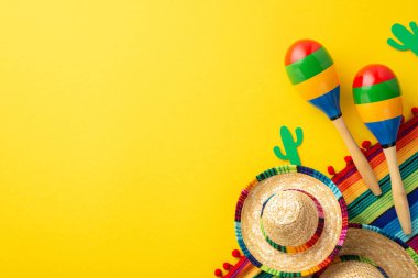 Cinco-de-mayonez konsepti. Sombrero şapkalarının üst görüntüsü renkli çizgili serape kaktüs siluetleri ve izole edilmiş parlak sarı arka planda boş alan ile birkaç marakas.