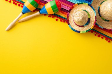 Cinco-de-mayonez parti konsepti. Meksika geleneksel şapka sombrero renkli panço ve izole edilmiş, parlak sarı arka planda, çift marakas.