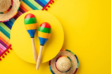 Cinco-de-mayonez karnavalı konsepti. Sarı daireli birkaç marakanın üst görüntüsü geleneksel şapkalar ve izole edilmiş sarı arka planda renkli çizgili seraplar.