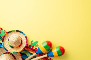 Cinco de Mayo kutlama konsepti. Meksika sombrero renkli panço maraktüs kaktüsünün en üstteki düz fotoğrafı. Pastel sarı arka planda izole edilmiş ve fotokopi alanı var.