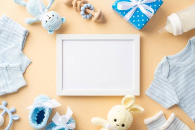 Bebek oğlan konsepti. Fotoğraf çerçevesi mavi gömlek pantolon çoraplar örgü ayakkabılar hediye süt şişesi çıngırak ve izole edilmiş pastel bej arka planda boş alan