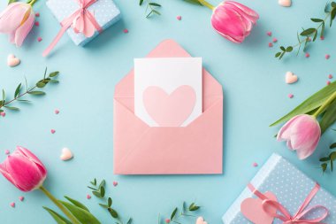 Anneler Günü konsepti. Açık pembe zarf kartpostalının en üstteki resmi. İçinde kalp bahar çiçekleri var. Kutular, küçük kalpler ve izole edilmiş pastel arka planda serpiştirmeler.