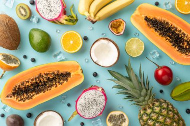 Cennet konsepti. Taze ejderha meyvesi, kivi, papaya, ananas, portakal, limon, muz, avokado, mavi arka planda hindistan cevizi.