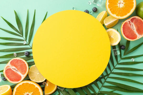 Citrus temptation concept. Top view of sliced juicy oranges, lemons, limes and grapefruits on turquoise background with empty circle for promotional text