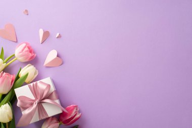 Anneler Günü hediye kutusu konsepti. En üstteki düz pembe kutular, kurdeleli, lale çiçekli, yumuşak pastel menekşe arkaplanlı kağıt kalpler, metin veya reklam için boşluk.