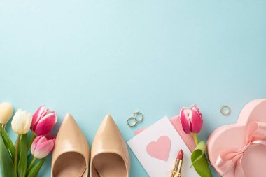 Güzel Anneler Günü konsepti. Yüksek topuklu ayakkabılar, hediye kutusu, laleler, ruj, pastel mavisi arka planda mesaj ya da reklam alanı olan bir kartpostal.