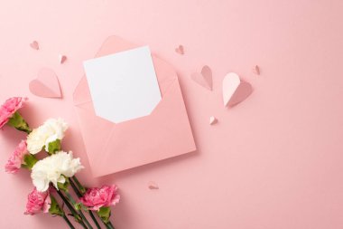 Üstten görünüşlü düz bir zarf, açık bir zarf, güzel karanfil çiçekleri ve yumuşak pembe arka planda pembe kağıt kalpler.