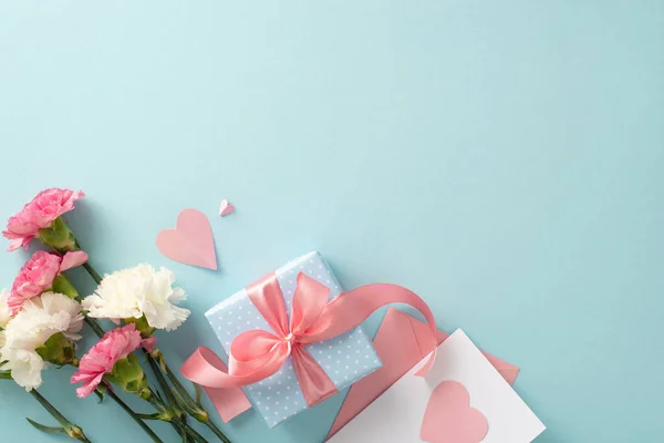 母亲节庆祝的概念 顶部视图平面放置的礼品盒照片 礼品盒上有粉色缎带 康乃馨花和粉色纸心 背景为淡蓝色 空白处有文字或广告 — 图库照片