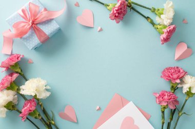 Anneler günü sürpriz hediye konsepti. Üst manzara düz fotoğraf pembe kurdeleli güzel hediye kutuları, karanfil çiçekleri, ve pastel mavi arka plan üzerinde pembe kağıt kalpler
