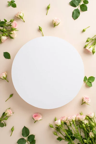 Minimalist but captivating top vertical view of small roses on a calming beige surface, complete with an open area in shape of circle for promotional messaging or branding