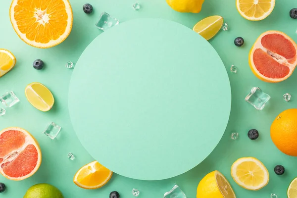 Citrus sensation concept. Top view of sliced juicy oranges, lemons, limes and grapefruits on turquoise background with empty circle for promotional text