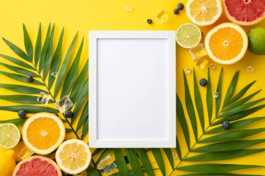 Açık sarı arkaplanda yeşil palmiye yapraklı sulu portakallar, limonlar, limonlar ve greyfurtların üst görünüm resimlerinde, metin veya logolar için ideal boş bir çerçeve yer almaktadır.