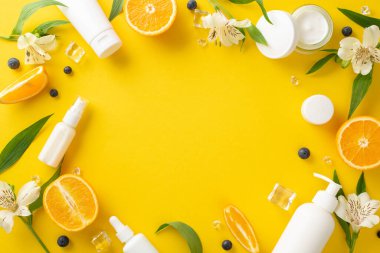 Lezzetli yaz teni konsepti. Üst görünüm düzlüğü, sahte krema şişeleri, kavanozlar, serum, turuncu çiçekli pipet, açık sarı arka plan, mesaj veya reklam için boş alan