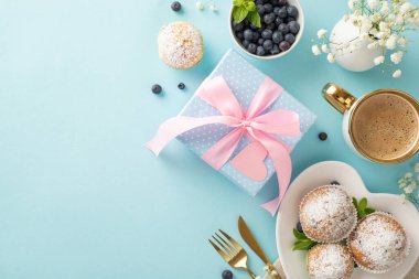 Annene sevgilerini göster. Üst kattaki daire çörekler, hediyeler, bir fincan sıcak kahve ve pastel mavisi arka planda çingene çiçekleri. Anneler Günü için uygun bir karşılama mesajı ya da reklam.