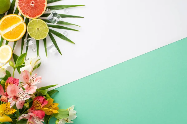 stock image Vibrant fruit feast concept. Top view flat lay of alstroemeria flowers with juicy orange, grapefruit, and lime slices on white teal background with copyspace for text or advert