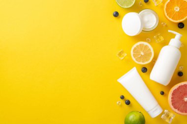 C vitamini yaz cilt bakımı. Üst görünüm düzlüğü, sahte krema şişeleri, kavanozlar, serum, açık sarı arka planda turuncu greyfurt limonu, mesaj veya reklam için boş alan.