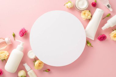 Yumuşak çiçek derisi konsepti. Üst görünüm pompa şişesi, boru, krem şişeleri ve pembe çiçekli tüpler pembe arka planda boş daire ile metin veya markalaşma için