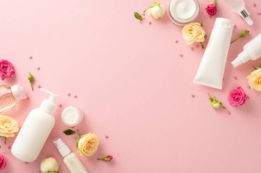 Doğal botanik cilt konsepti. Pompa şişesi, boru, krem şişeleri ve pastel pembe arka planda çiçekli tüpler. Metin veya damgalama için boş alan var.