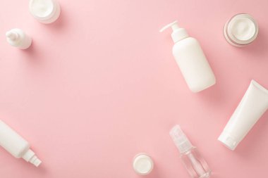 Nazik güzellik konsepti. Üst görünüm pompa şişesi, boru, krem şişeleri ve tüplerin düz yatağı pastel pembe zemin üzerinde metin veya markalaşma için boş alan ile