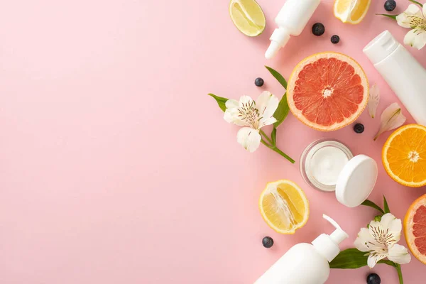 stock image Trendy summer fruit skincare concept. Top view flat lay of mockup cream bottles, jars, serum, pipette with citrus and flower on pastel pink background. Empty space for text or advert