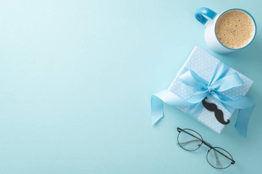 Sınıfla Babalar Günü anlaşması. Gözlük, bıyık, hediye kutusu, kahve fincanı ve pastel mavi arkaplan üzerine yazı yazmak için boş alan.