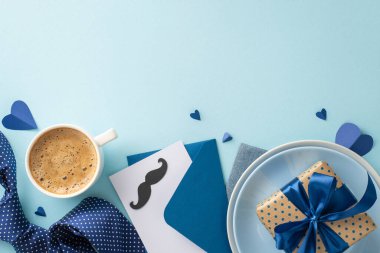 Babalar günü sürprizi ve çarpıcı bir masa hazırlama fikri. Tabakların üst görüntüsü, kahve, hediye kutusu, kravat, zarf, bıyıklı kart, pastel mavi arkaplan ve boş alan.