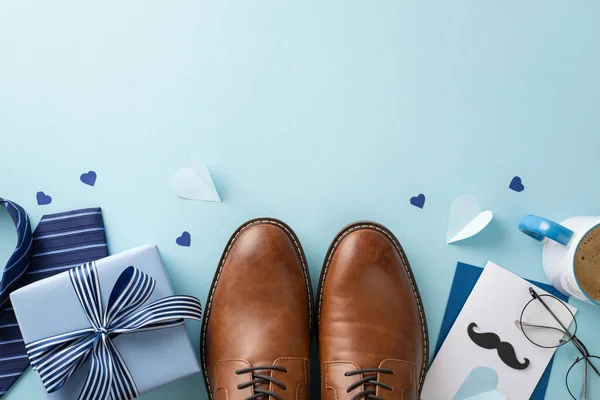 stock image Chic Father's Day theme. Overhead shot of leather shoes, necktie, spectacles, giftbox, envelope with postcard, paper hearts, and coffee cup on pastel blue surface with blank space for text