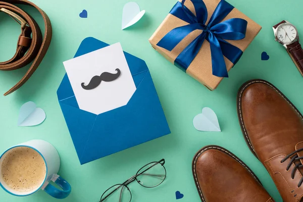 stock image Fashionable Father's Day concept. Top view flat lay arrangement of open envelope, postcard with mustaches, gift box, leather shoes, wristwatch, accessories, belt, hearts, spectacles on teal background