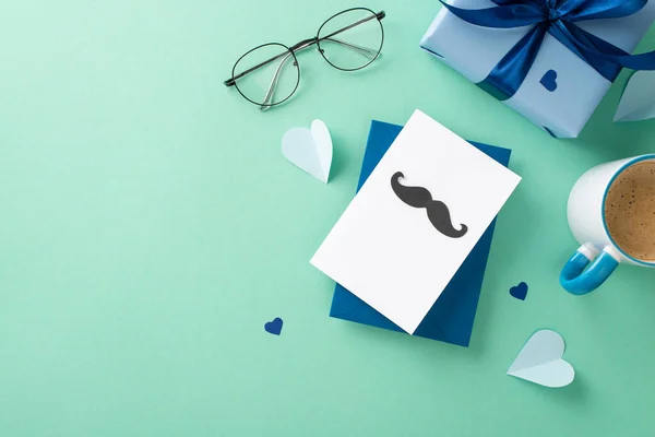 stock image Fashionable Father's Day scene. Overhead image of postcard with mustaches, ribbon bow giftbox, paper hearts, spectacles, coffee mug on turquoise background with an empty space for advertising